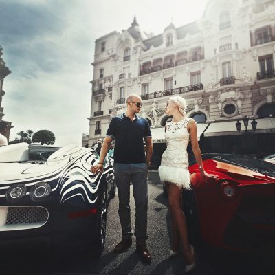 Couple stands between Bugatti and Lamborgini somewhere in Monte Carlo